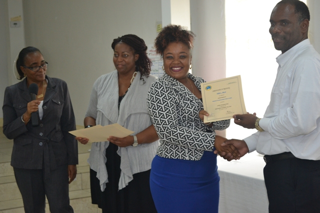 Permanent Secretary in the Ministry of Finance Colin Dore (right) presents a certificate of training to Vieda Mills at the closing ceremony of a Caribbean Development Bank funded training workshop at the St. Paul’s Anglican Church Hall on April 14, 2016. Facilitators Catherine Forbes (left) and Nicole Liburd are assisting with presenting certificates to participants